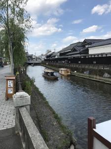 TochigiGuest House Kuranomachi ゲストハウス蔵の街的一条河,河里有船,有一座建筑