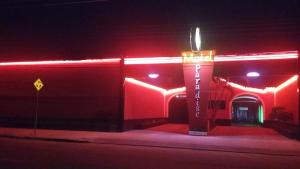 圣若泽杜斯坎普斯Motel Paradise (Adults only)的一座红色的建筑,晚上在它前面有标志
