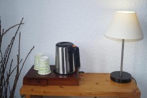 Hières-sur-Amby昂比河谷酒店的台灯旁的桌子上的咖啡壶