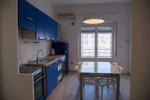 格罗塞托港Wonderful house in Marina di Grosseto的厨房配有蓝色橱柜和带玻璃桌的小桌子。