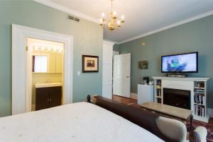 滨湖尼亚加拉Historic Lyons House的一间卧室配有一张床、一台电视和一个壁炉