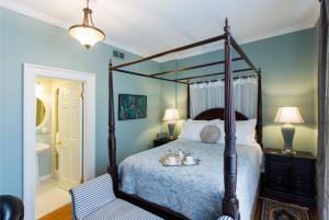 滨湖尼亚加拉Historic Lyons House的一间卧室设有天蓬床和一间浴室。