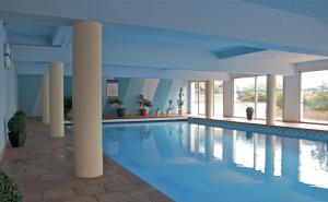 基伯龙欧罗巴酒店的一座带柱子的建筑里的大型游泳池