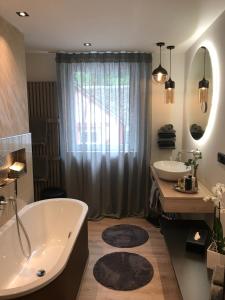 科赫姆摩泽尔公寓的带浴缸和两个盥洗盆的浴室以及大窗户。