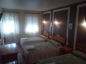 JarrioHotel Restaurante Las Camelias的酒店客房设有两张床和一张桌子。