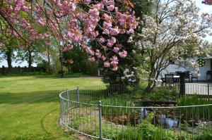 特雷勒堡Minnesberg Bed & Breakfast的树前有粉红色花的栅栏