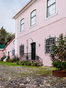 Cruz QuebradaVilla Marquês near Tejo River的前面有一条鹅卵石街道的粉红色房子