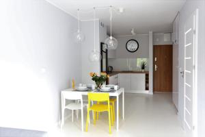 尤斯托尼莫斯基Apartamentowiec Dwie Sosny的厨房配有白色的桌子和黄色的椅子
