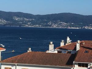 桑亨霍Playa Silgar en Galicia的享有水景和建筑屋顶的景色