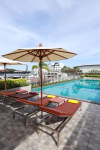 芭堤雅市中心耳语酒店的一个带几把躺椅和遮阳伞的游泳池