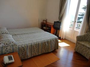 PremenoHotel Villa Rosy的一间卧室设有一张床、一台电视和一个窗口。