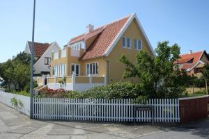 斯卡恩Østre Strandvej 49的黄色房屋,有白色的栅栏
