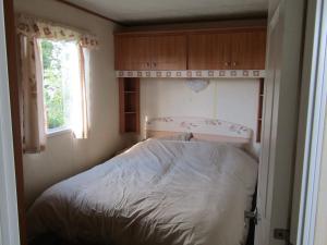 MetheringhamFenlake holiday accommodation的一个小房间的一个床位,设有窗户