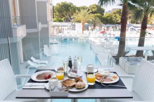 帕尔马诺瓦Reverence Mare Hotel - Adults Only的一张桌子,旁边是游泳池,提供早餐食品和饮料