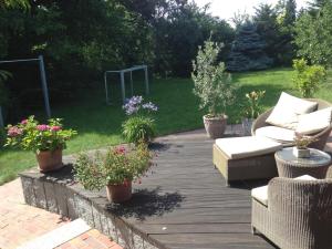 基尔Ferienwohnung Kiel-Russee的木甲板,配有沙发和一些植物