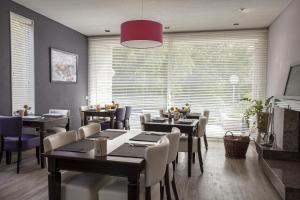 玛库姆Lodgehotel de Lelie的餐厅设有桌椅和大窗户。
