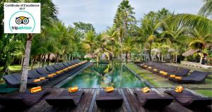 乌布曼森Spa度假酒店的度假村的游泳池,设有躺椅和棕榈树