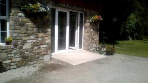 BroadfordWalkers Lodge的白色门和鲜花的石头房子