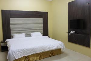艾卜哈Rayanat Abha Aparthotel的一间卧室配有一张大床和一台平面电视