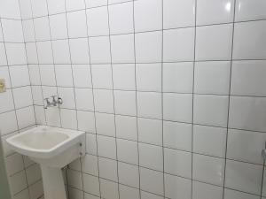 巴西利亚Asa Norte的浴室设有白色瓷砖墙和水槽。