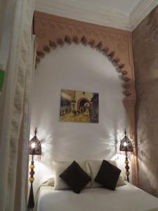 丹吉尔阿鲁斯卡梅尔摩洛哥传统庭院旅馆的卧室配有带两盏灯的白色床