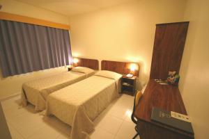 伊塔佩瓦Patriarca Hotel的酒店客房设有两张床和电视。