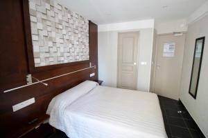巴黎比利牛斯酒店的一间小卧室,配有一张床和一个木制床头板
