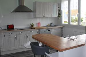 圣马洛Appartement lumineux et Agréable 6 Personnes的厨房配有白色橱柜和木桌