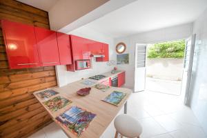 圣安娜Residence fruit de la passion F4的厨房配有红色橱柜和木桌