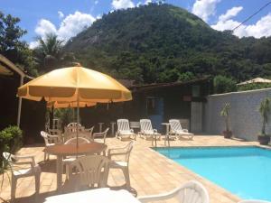 瓜皮米林Pousada Nascente Pequena的游泳池旁配有遮阳伞的桌椅