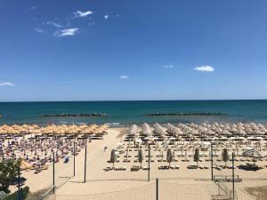 奥托纳Hotel La Bussola的海滩上设有遮阳伞和椅子,还有大海