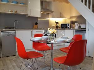 科尔福德Pomegranate的厨房配有桌子和红色椅子