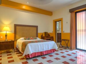 梅里达Hotel Luz en Yucatan的一间卧室配有一张床、一张桌子和一个窗户。