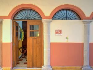 梅里达Hotel Luz en Yucatan的一座带两个拱门和木门的房子