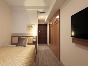 神户神户三宫优尼佐酒店的一间卧室配有一张床和一台平面电视