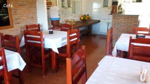 沙帕达-杜斯吉马朗伊斯Pousada Portal的一间带白色桌椅的餐厅和一间厨房
