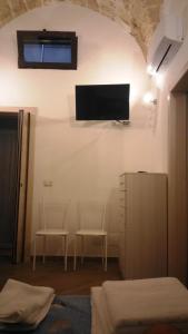 诺沃利Salento's Casettina的卧室配有两把椅子和墙上的电视。