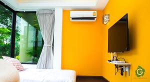 武里南武里南府格林酒店的黄色的房间,设有床和电视