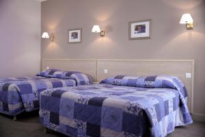 凡尔赛杜柴威璐芝酒店的配有两张蓝色和白色床单的床铺
