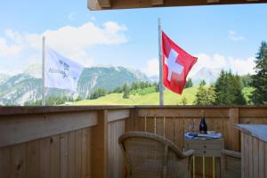 茨韦西门瑞德包瑞士高山小屋旅馆的阳台配有两面旗帜、一张桌子和一把椅子
