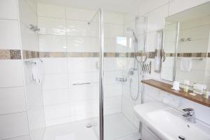 巴特欣德朗普林茨露博德酒店的带淋浴和盥洗盆的白色浴室