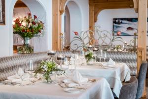 莱赫阿尔贝格奥尤恩霍夫酒店的用餐室配有白色的桌子和鲜花