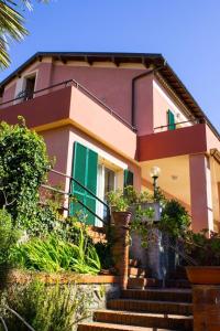 迪亚诺马里纳Hotel La Margherita的前面有绿色百叶窗和楼梯的房子