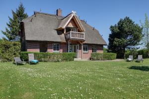 洛默Haus Sonnenblume的庭院内带茅草屋顶和椅子的房子