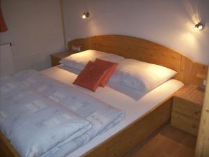 大格洛克纳山麓卡尔斯Haus Gartenheim的一张带木制床头板和白色枕头的床