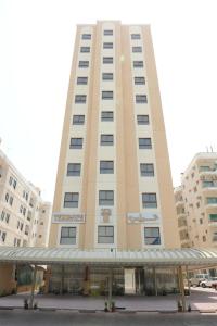 科威特莎米亚带露台家具的公寓的一座高大的棕褐色建筑,前面有一个停车位
