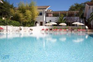 努马纳Hotel Giardino Suites&Spa的一个带椅子和遮阳伞的大型游泳池