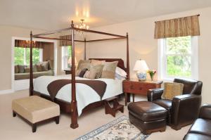 卡南代瓜1795 Acorn Inn Bed and Breakfast的一间卧室配有一张天蓬床和一把椅子