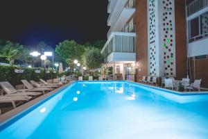 米兰马瑞提那里多尔菲酒店的一座带椅子的夜间游泳池和一座建筑
