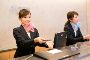 名古屋名古屋站贾斯特尊贵酒店的两名穿着西装的女士坐在一张桌子上,手提电脑